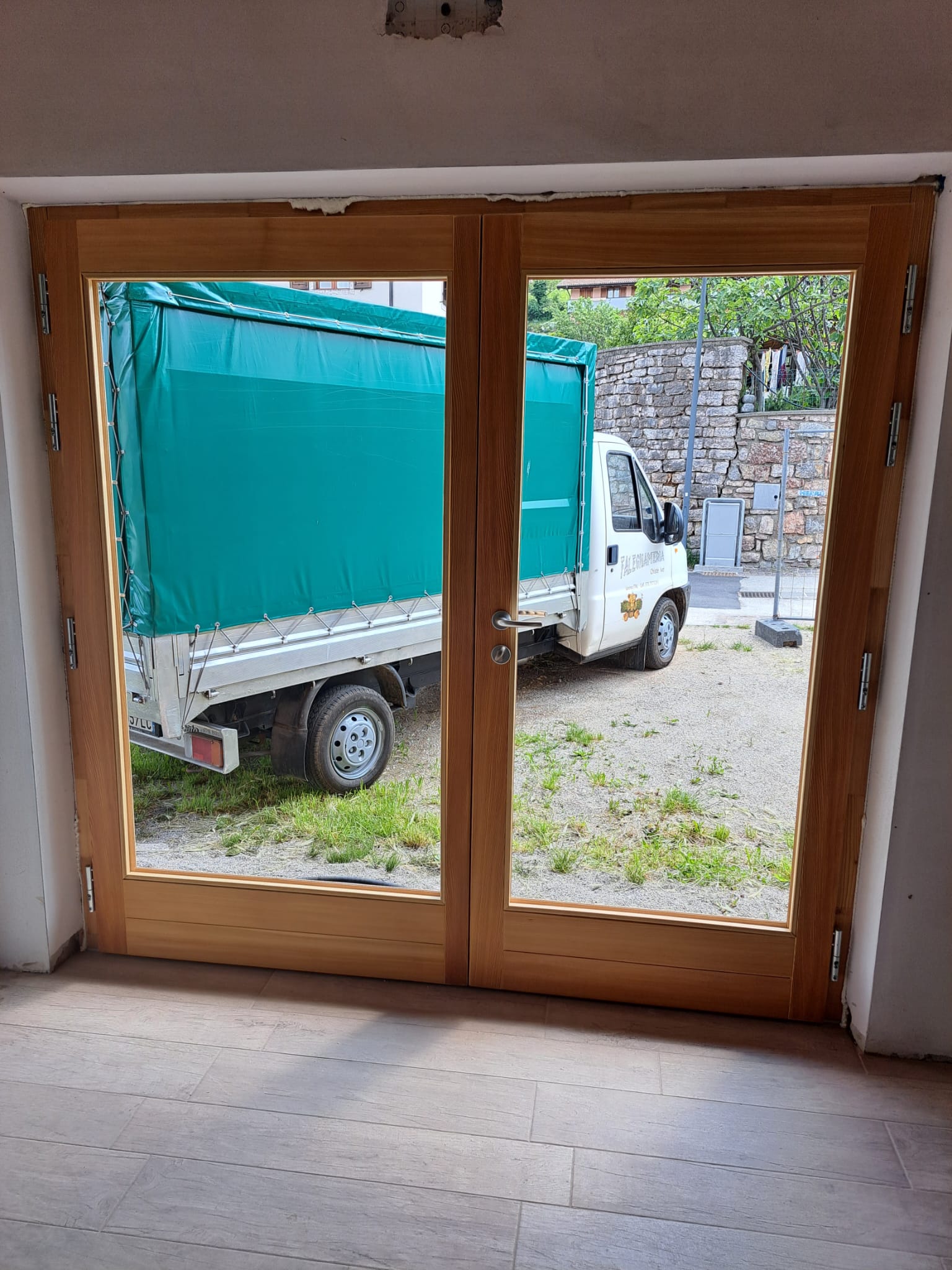 Dettaglio del progetto Porta Finestra in Legno: Porta finestra realizzata in legno massello con profili strutturali robusti e superficie vetrata ampia. - Immagine 1